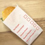 Burger bags with tick box feature, made from greaseproof material for efficient takeaway service. Burger bags with tick box in a takeaway shop, ideal for cheeseburgers, chicken burgers, and quarter pounders.