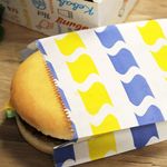 5x8 inch grease-resistant burger bag securely holding a burger, ensuring mess-free transport for customers. Grease-resistant treated burger bag preventing leaks and stains, ensuring clean and safe food transport.
