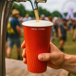 Red paper pint cup holding beer, alcohol-safe and ideal for pubs, bars, and outdoor events.