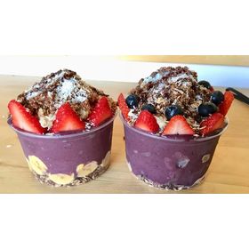 Close-up of fresh açaí topped with berries inside a crystal-clear food container for retail presentation